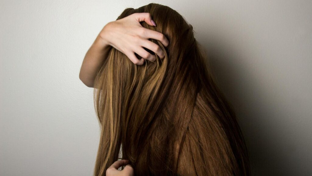 Woman covering her face with her hair, smiling playfully