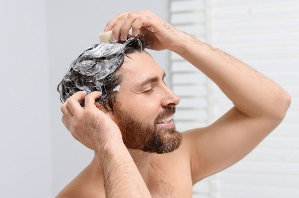 Man shampooing hair with smile