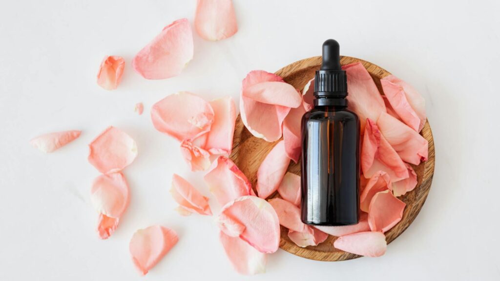 Close-up of hands applying cuticle oil with a dropper bottle, featuring text 'DIY Natural Easy Cuticle Oil Recipe.