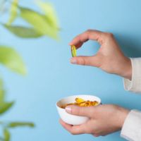 A person holding a bowl of supplements and picking a capsule, supporting eczema management naturally