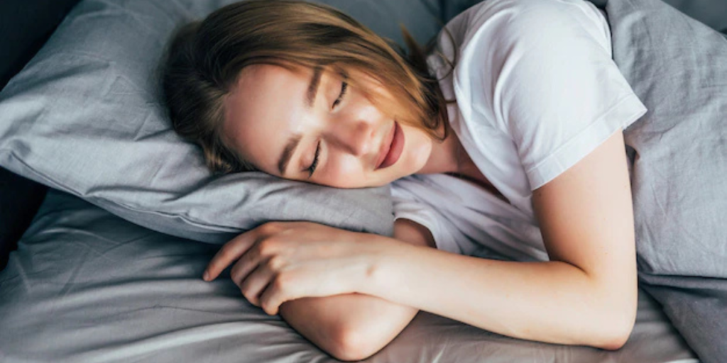 A young woman with flawless glowing skin sleeps peacefully on a soft pillow, radiating relaxation and beauty